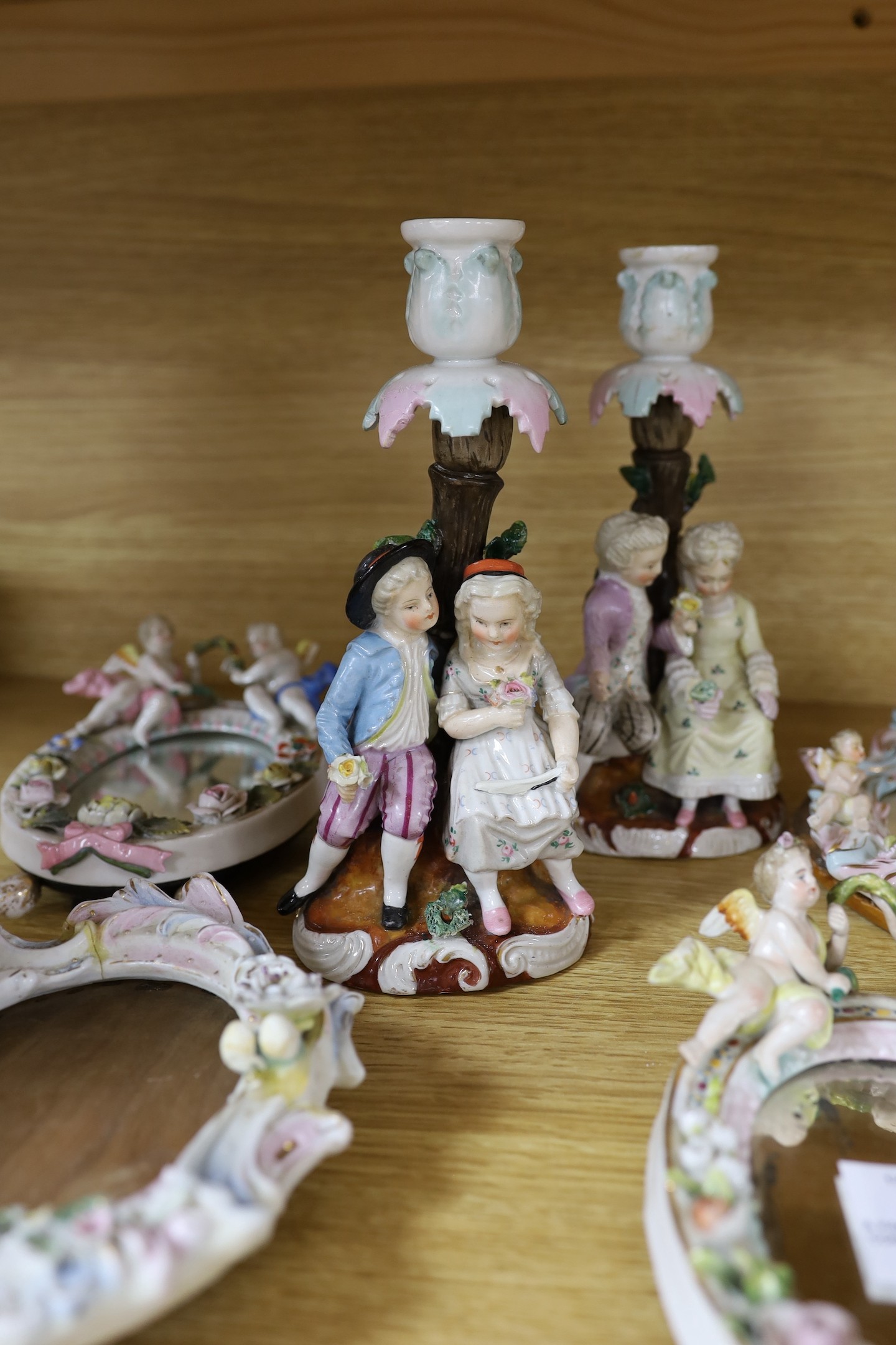 A pair of 19th century continental porcelain figural candlesticks and a group of four similar frames